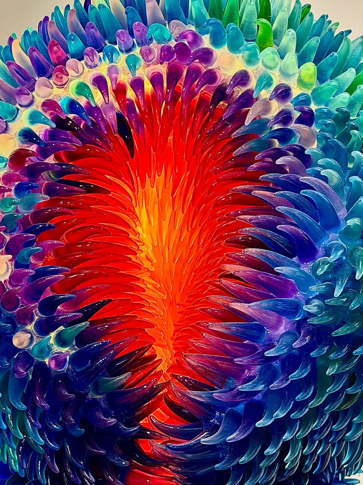 A colorful sculpture with curved blue, turquoise, and purple forms surrounding a bright orange-red center